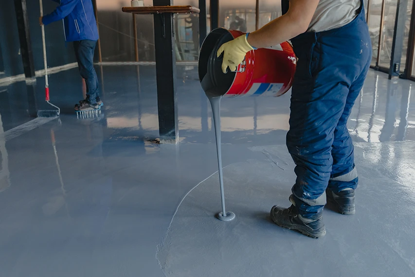 Worker applying waterborne floor coating with HEC support