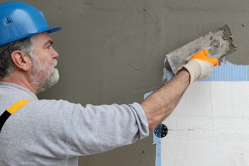 Worker applying EIFS base coat with HEMC support