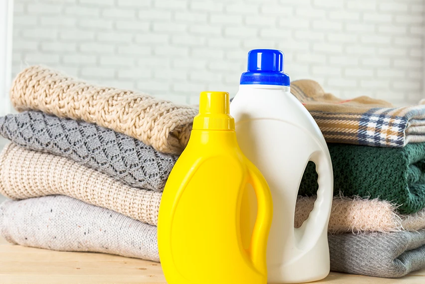 Laundry detergent bottles placed with folded towels, representing HEMC use in liquid laundry detergent formulations for viscosity control, stable texture, and smooth product appearance.
