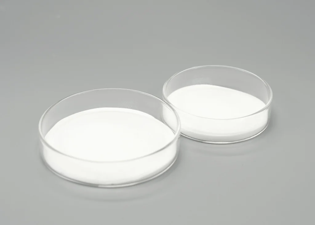 Pure white HEMC powder (Hydroxyethyl Methyl Cellulose) displayed in a clear glass container.