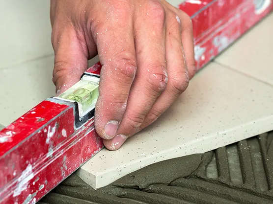 Tile or board being pressed onto adhesive mortar, showing HEMC 100H use in tile fixing and bonding applications.