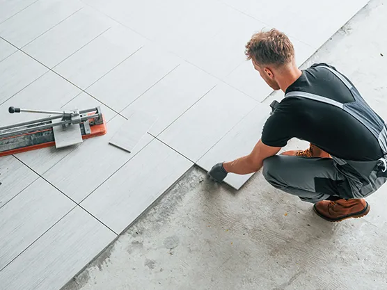 Worker installing floor tiles with adhesive mortar, showing HEMC 150H use in tile adhesive and flooring applications.